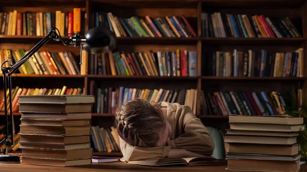 피곤 한 여학생 이 식탁에 놓인 책들 가운데서 책을 읽고 잠을 잡니다 — 스톡 사진