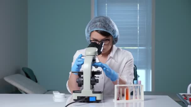 Lady justerar mikroskop arbetar med prov på sjukhus — Stockvideo