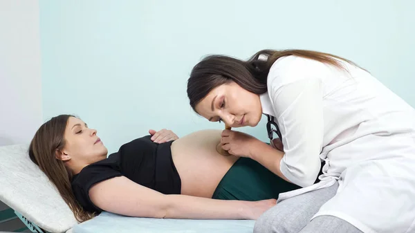 Arzt legt Fötus auf Schwangerschaftsbauch im Krankenhaus — Stockfoto