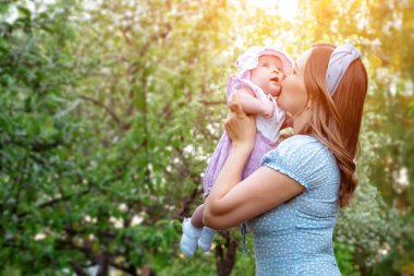 Sarı saçlı, mavi elbiseli genç kadın küçük kızını kucağına aldı.