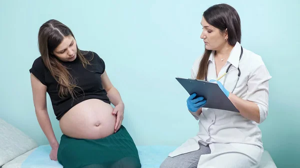 주의깊은 의사는 진료소에서 임신부의 배에 손을 댄다 — 스톡 사진