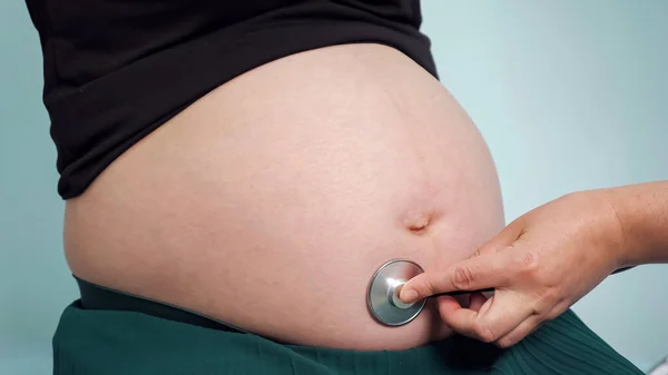 Médecin écoute femme enceinte avec stéthoscope en clinique — Photo