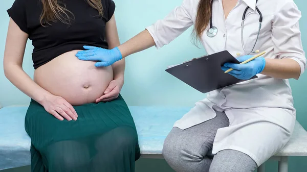 쇼파에서 임신 한 환자를 검진하는 클립보드를 가진 의사 — 스톡 사진