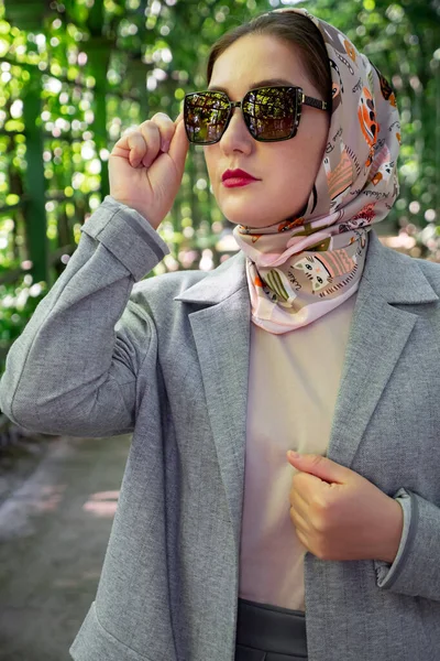 Portrait de dame musulmane élégante en costume gris et des lunettes de soleil pose au parc, tendance de style de mode — Photo