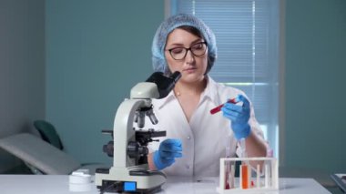 Laboratuvar asistanı hastanede test tüpünü kırmızı sıvıyla salladı.