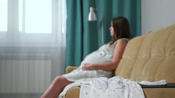 Close-up van pasgeboren kleren op wazig zwangere vrouw achtergrond — Stockvideo