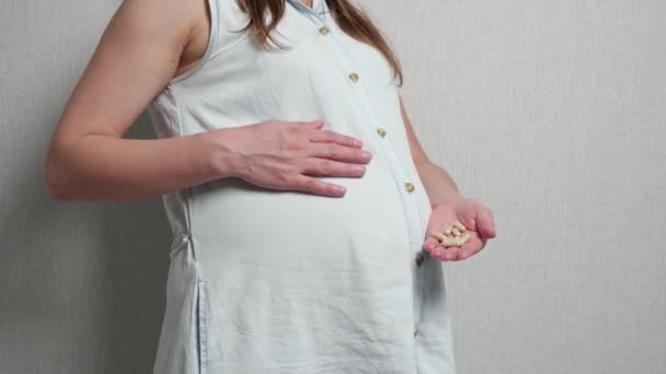 Femme enceinte méconnaissable caressant le ventre tout en tenant des capsules dans l'autre main — Video