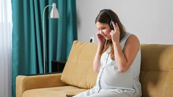 Femme enceinte appréciant écouter de la musique sur écouteurs — Photo