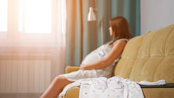 임신 한 여성의 배경 이 흐릿 한 신생아 옷을 클로즈업 한 모습 — 스톡 사진