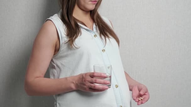 Young pregnant woman drinks medicine with water — Stock Video