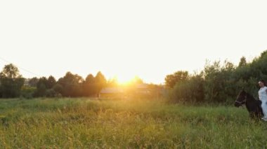 Beyaz elbiseli profesyonel bayan binici kahverengi ata biniyor.