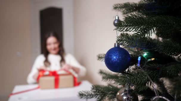 Primer plano del árbol de Navidad con fondo borroso de regalo de apertura de mujer — Vídeos de Stock