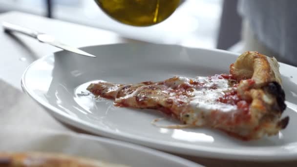 Persona que vierte la adición de aceite de oliva a rebanadas de pizza. — Vídeos de Stock