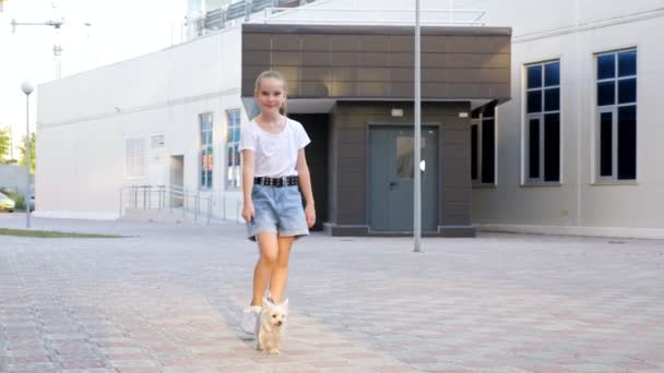 Teenage girl walks with puppy on leash on yard pavement — Stock Video