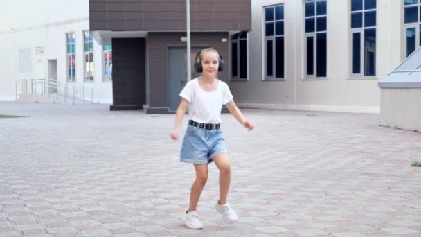 Ung tonåring i t-shirt shorts och hörlurar danser — Stockvideo
