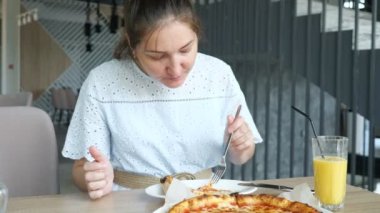 Restoranda pizza yiyen bir kadın.