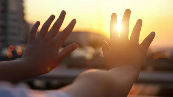 Schoolgirl hands on bridge against bright sunset closeup