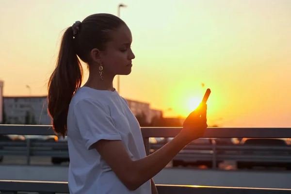 Зависимая девочка-подросток с хвостиком держит смартфон — стоковое фото
