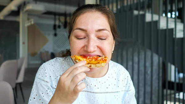 Mujer joven come sabrosa pizza disfrutando en la cafetería —  Fotos de Stock