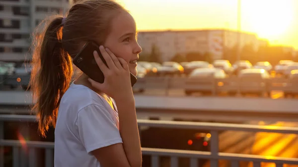 Iskoláslány beszél okostelefonon koncentrációval naplementekor — Stock Fotó