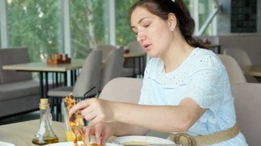 Mavi elbiseli güzel esmer kadın restoranda pizza yiyor.