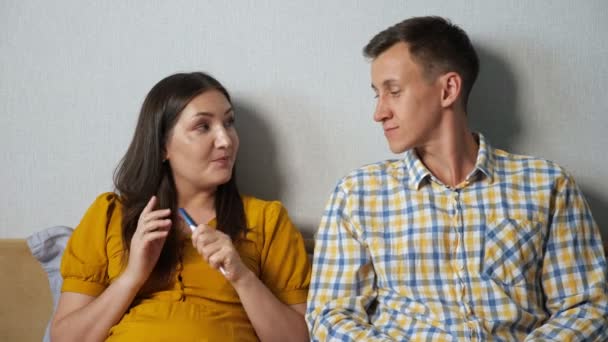 Hombre y mujer mirando con entusiasmo el resultado de la prueba de embarazo mientras están sentados en la cama — Vídeos de Stock