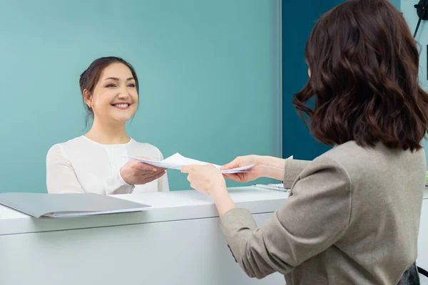 Receptionist accepts documents from the female visitor — Stock Photo, Image