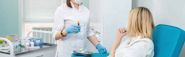 Unerkennbarer Labortechniker hält Blutgefäß und Patient mit angewinkeltem Arm sitzt auf Stuhl — Stockfoto