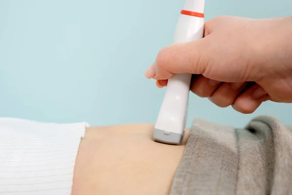 El médico hace ultrasonografía a la señora tocando el vientre con la herramienta — Foto de Stock