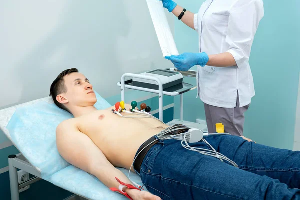 Profesional médico lleva un electrocardiograma a un hombre joven — Foto de Stock