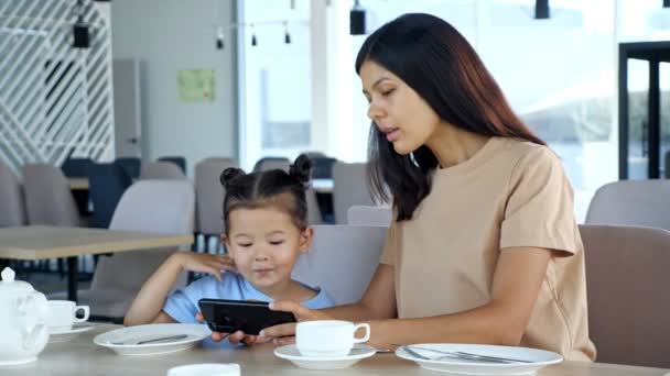 Jeune femme brune et petit enfant regarder la vidéo sur gadget — Video