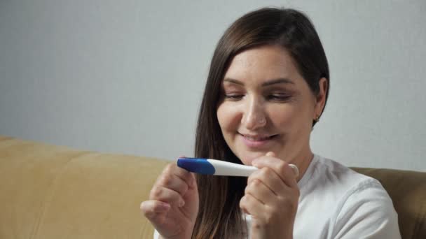 Κοντινό πλάνο της νεαρής γυναίκας που κοιτάζει χαρούμενα το τεστ εγκυμοσύνης — Αρχείο Βίντεο