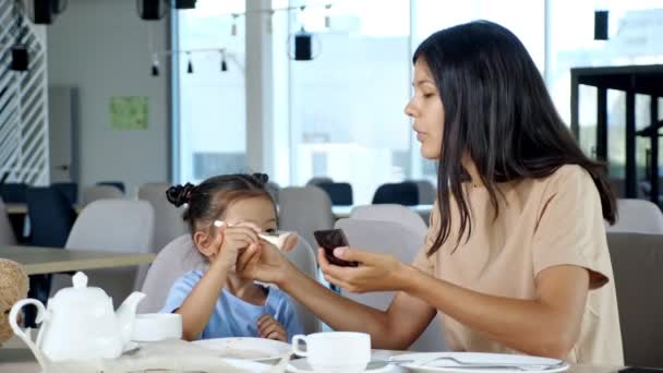 Маленька дочка допомагає мамі застосовувати макіяж . — стокове відео