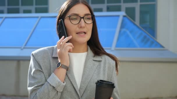 Mujer en traje formal hablando por teléfono y tomando café en la calle — Vídeos de Stock