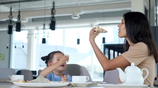 Radosna młoda kobieta brunetka mama i dziewczynka jeść przekąski — Wideo stockowe