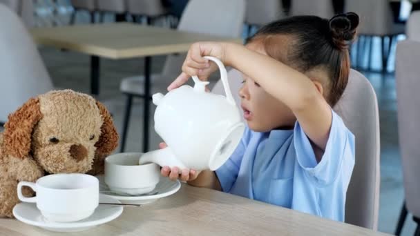 Zainteresowany Azji maluch dziewczyna wlewa herbatę do białych filiżanek — Wideo stockowe