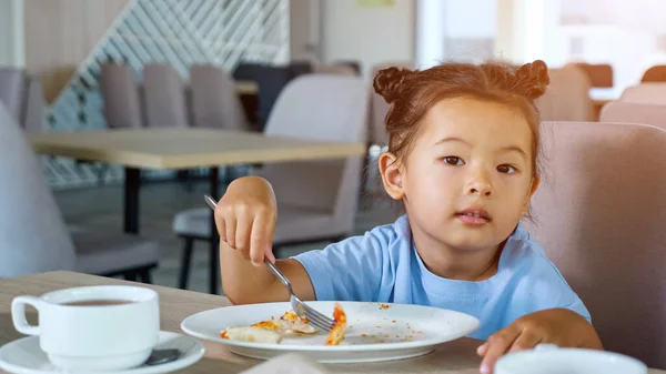 Маленькая девочка в голубой футболке ест вкусную пиццу — стоковое фото