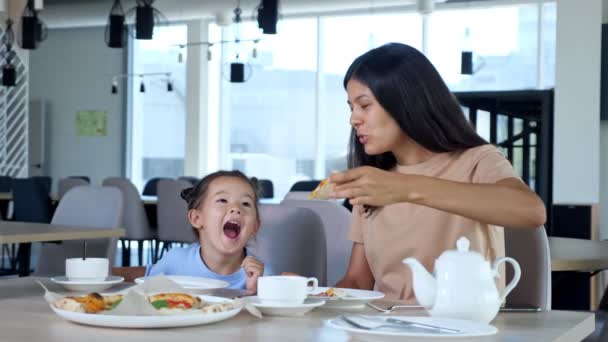 Молода мама тримає шматочок піци і дитина їсть грати — стокове відео