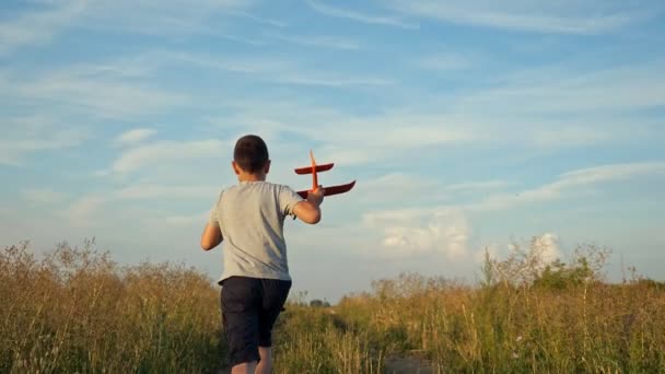 Jongen rent over het veld en speelt met een klein vliegtuig, slow motion — Stockvideo