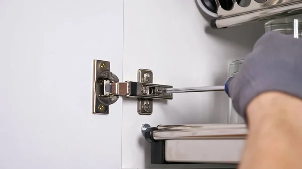 Employee installs door of cabinet twisting screws in hinges — Stock Photo, Image