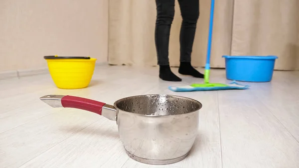 Water flows into pot from ceiling while woman mops floor — Stock Photo, Image