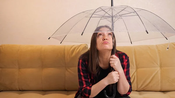Mujer pensativa se esconde del agua que fluye bajo el paraguas claro —  Fotos de Stock