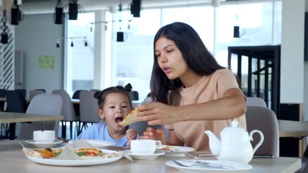Señora mamá sostiene rebanada de pizza y su hija come en la cafetería — Vídeos de Stock
