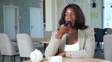 Afro-Amerikalı kadın kafede sesli mesaj kaydediyor.