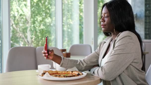 African-American woman makes selfie at table with pizza — Stock Video