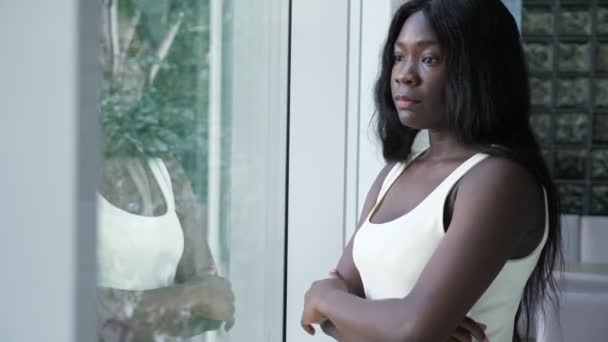 Molesto mujer afro-americana preocupada cerca de la ventana en casa — Vídeo de stock