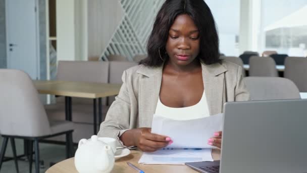 Femme d'affaires noire boit du thé feuilles de lecture dans le café — Video