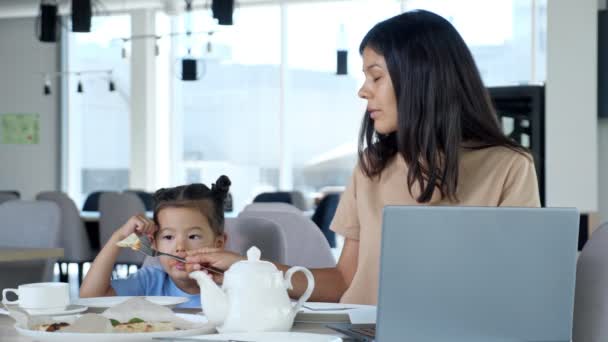 Bizneswoman mama daje pizzę dla dziecka siedzi przy stole — Wideo stockowe