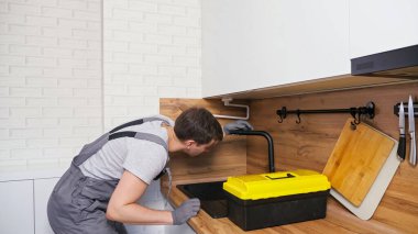 Alet kutulu tulumlu işçi musluktaki sızıntıyı arıyor