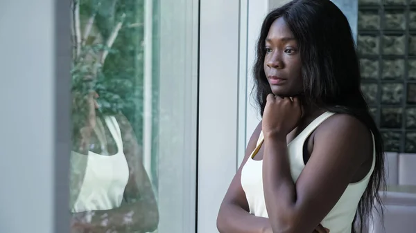 Upset worried African-American woman near window at home — Stock Photo, Image